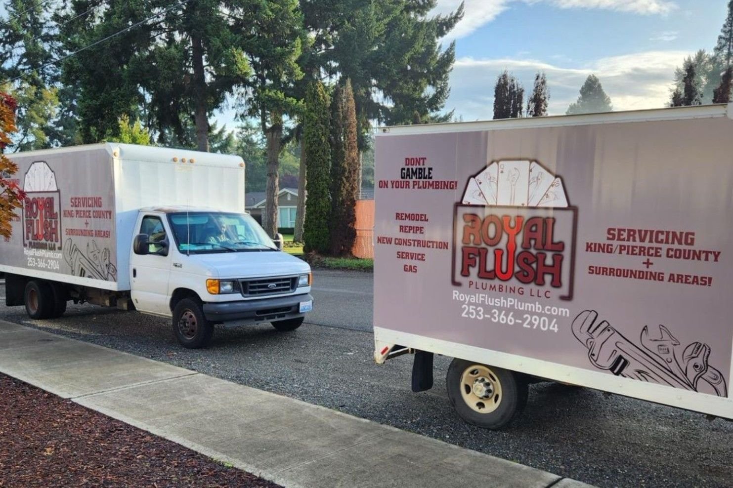 Two Royal Flush Plumbing service vans parked at a job site