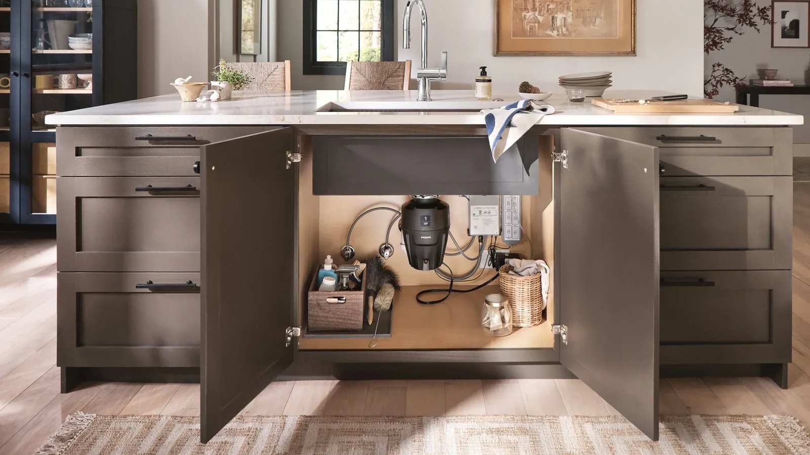 Garbage disposal mounted under a kitchen island sink with the cabinet doors open