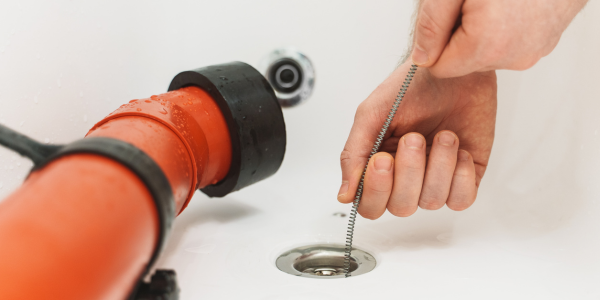 A plumber snaking a bathtub drain