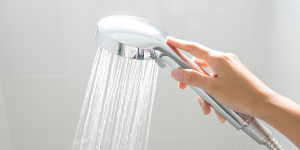 A hand holding a running shower head