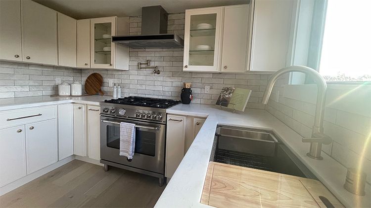 A kitchen with white cabinets, stainless steel appliances, a sink and a stove